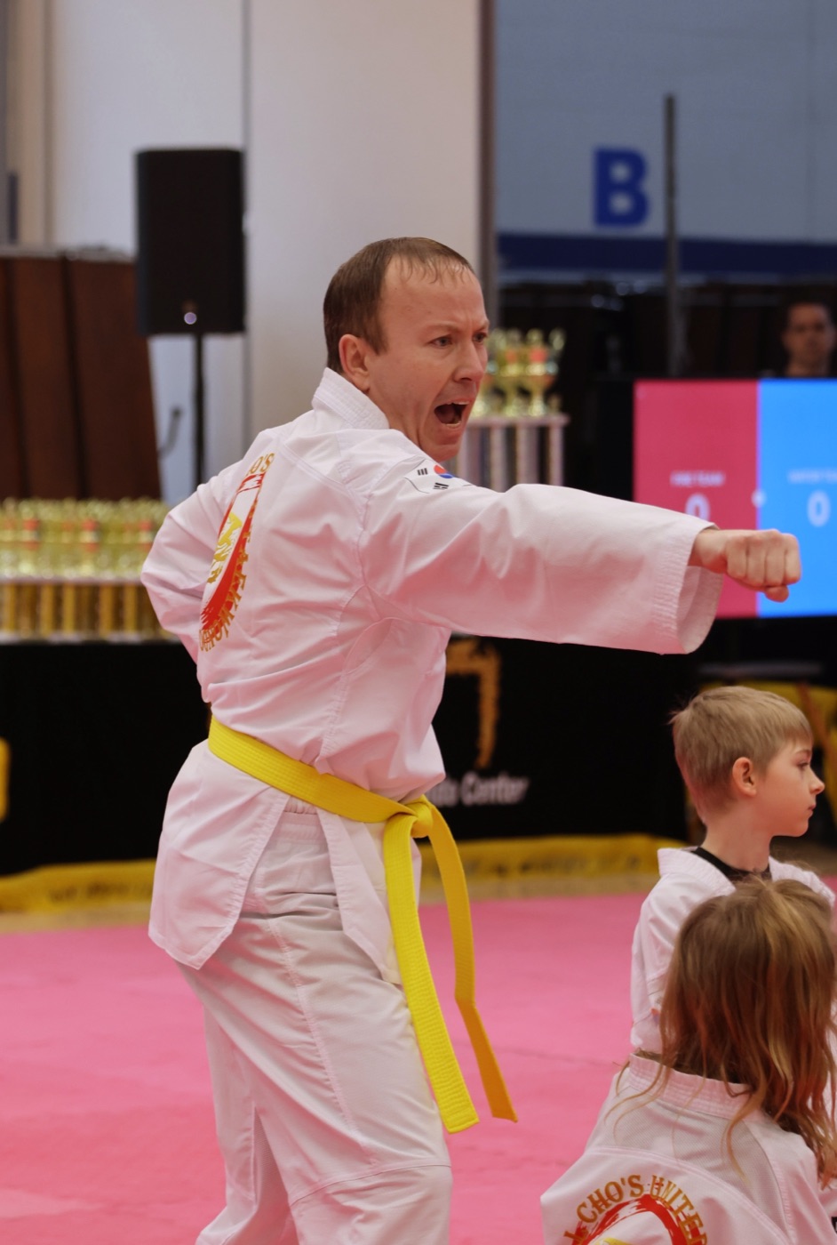 Adult Bill Cho's student with yellow belt mid-punch — proof it's never too late to begin